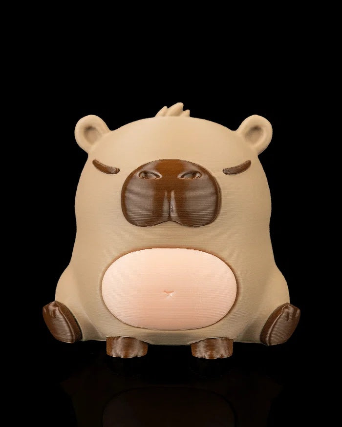Front view of a capybara figurine with a rounded seated body, dark muzzle, and pale belly.