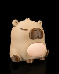 Three-quarter front view of a capybara figurine with rounded ears, a dark muzzle, and pale belly.