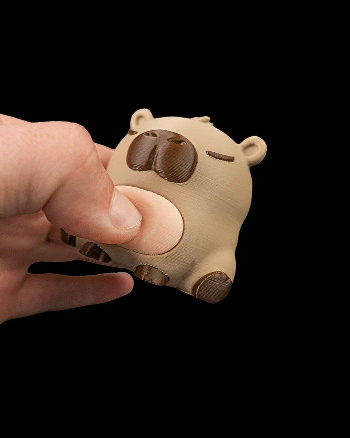 Hand pressing the pale belly of a capybara figurine.
