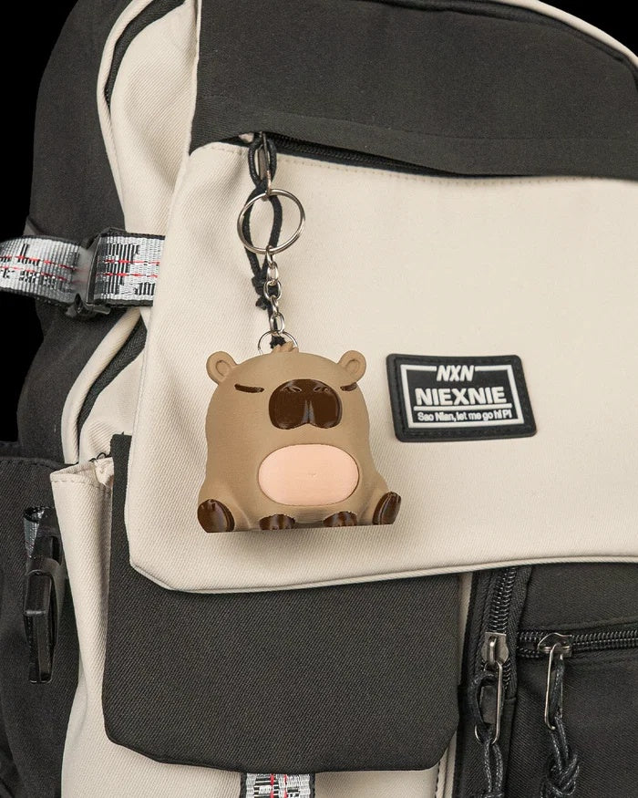 Capybara figurine hanging as a keychain from a backpack.