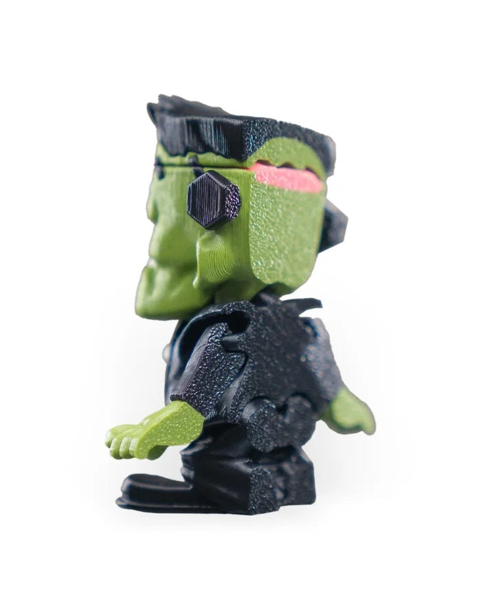 Rear three-quarter view of a spooky green monster figurine with a dark outfit and green head.