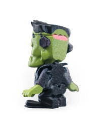 Rear three-quarter view of a spooky green monster figurine with a dark outfit and green head.