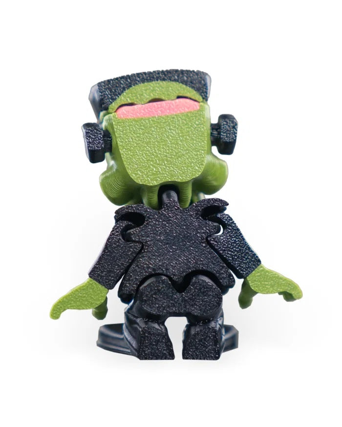 Back view of a spooky green monster figurine showing the black hair and dark outfit.