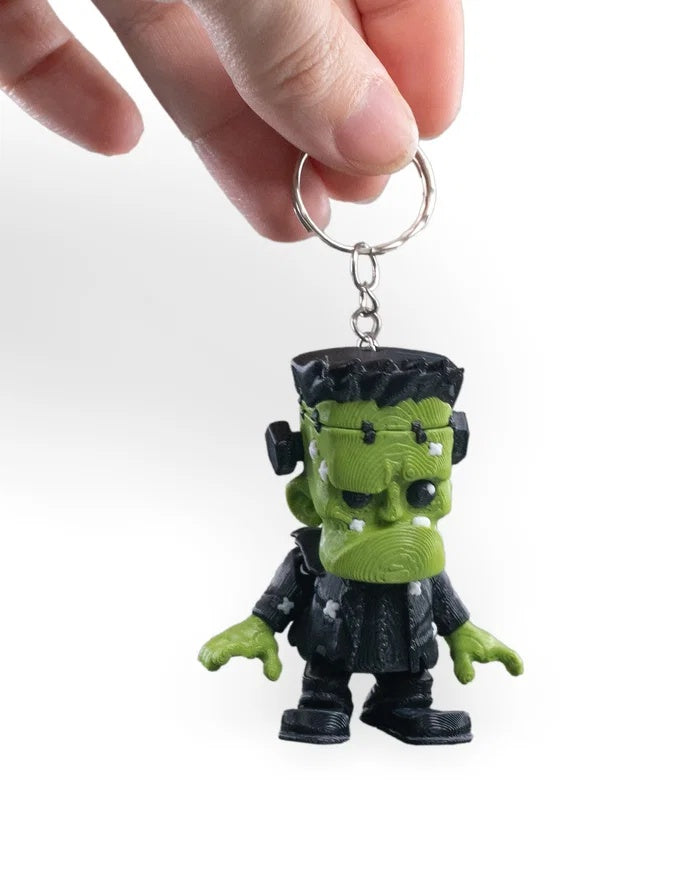 Alternate front view of a spooky green monster figurine held by a hand.